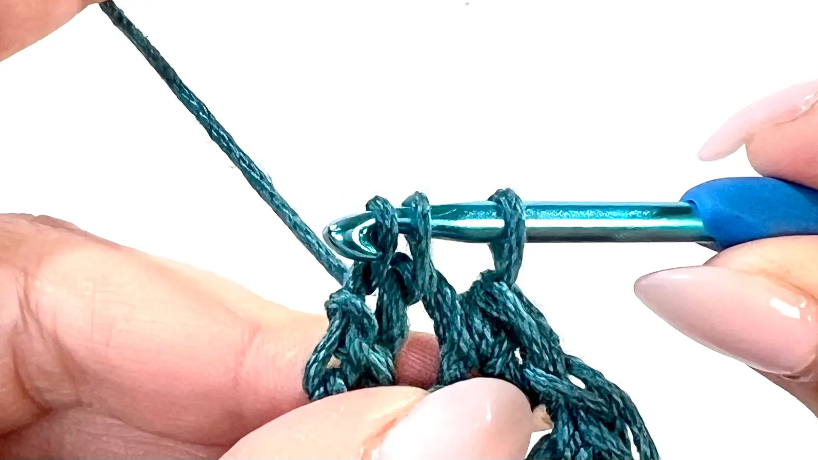 Final stitch of the decrease row being made into the last visible stitch; the row ends cleanly to continue the downward triangle shaping.