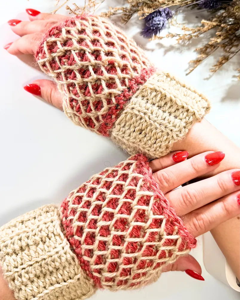 Fingerless crochet gloves with honeycomb stitch texture and ribbed cuffs, worn on hands.