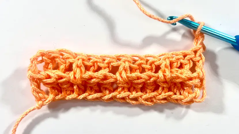 Detailed close-up of crochet waffle stitch texture being formed with front post and double crochets.