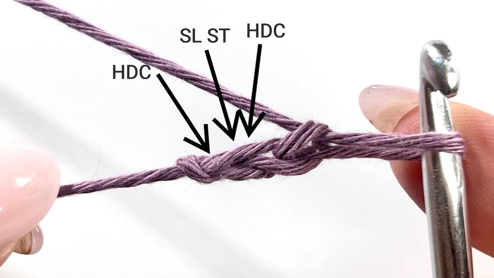 Close-up of a starting chain for C2C in Even Moss Stitch, made with light purple cotton yarn and a metal crochet hook. The yarn is held in position for the foundation step of the corner-to-corner method.