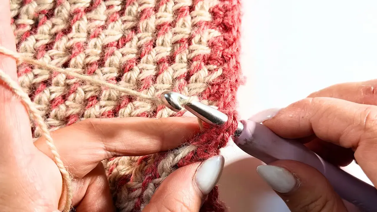 Close-up of the crochet hook inserted along the edge of the seamed and folded rectangle to begin the ribbing.