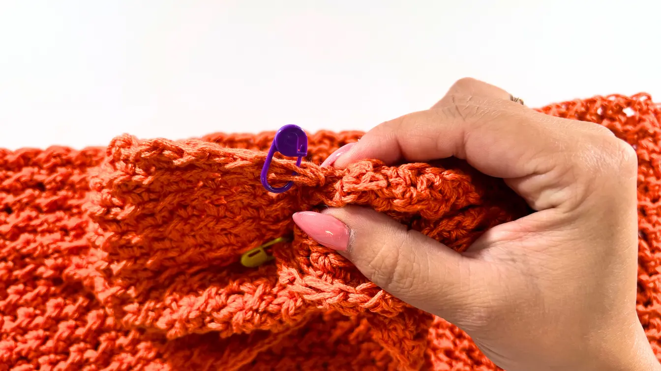 Placing a stitch marker on the edge of the twisted crochet top to mark where the bottom section will start.