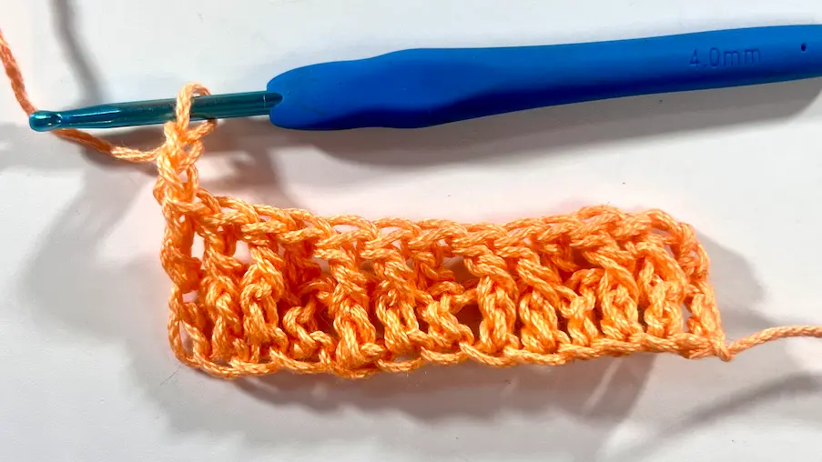 Detailed close-up of crochet waffle stitch texture being formed with front post and double crochets.