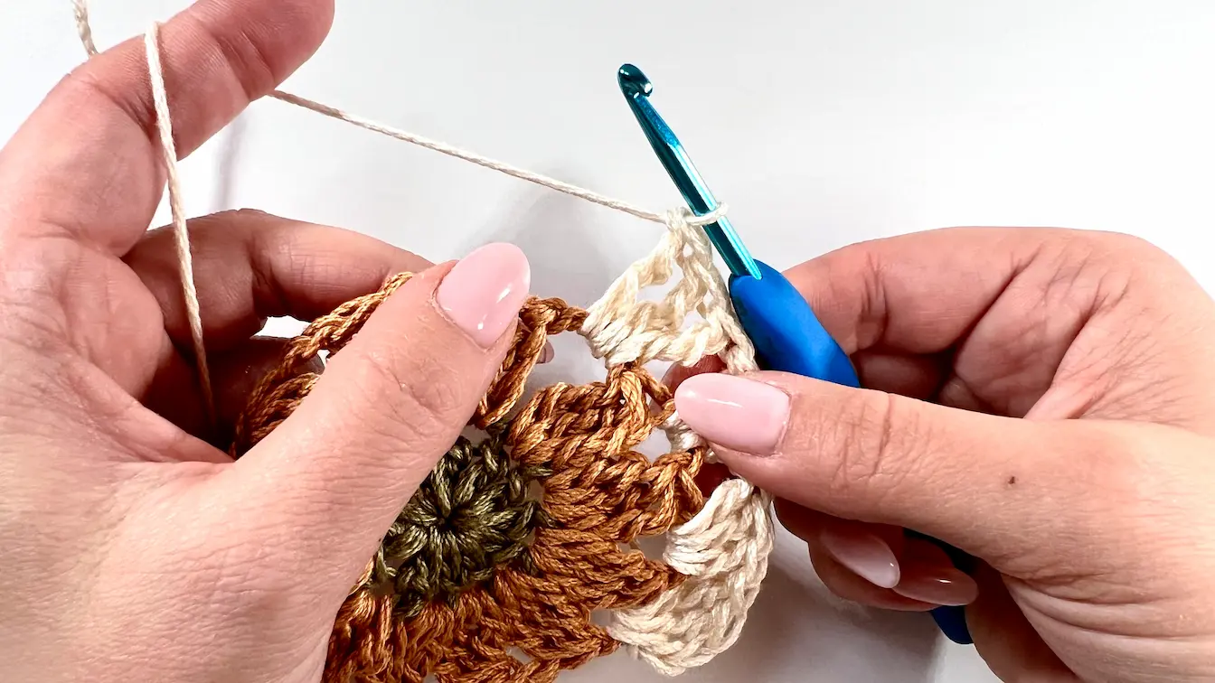 Working the first square corner using treble crochets and chain spaces on the Daisy motif.