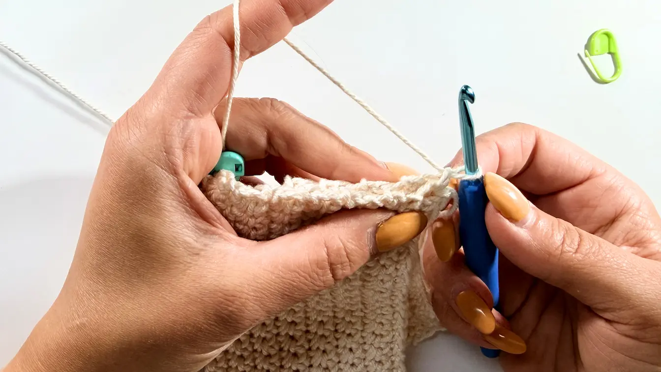 Close-up of two crochet panels being joined together along the edge using single crochet stitches.