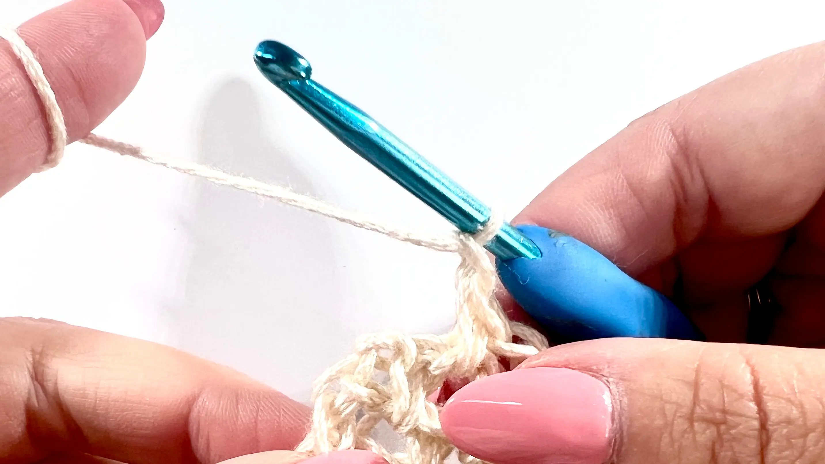  Close-up of a crochet hook holding two loops from the last single crochet stitch, ready to finish the stitch with a new yarn colour.
