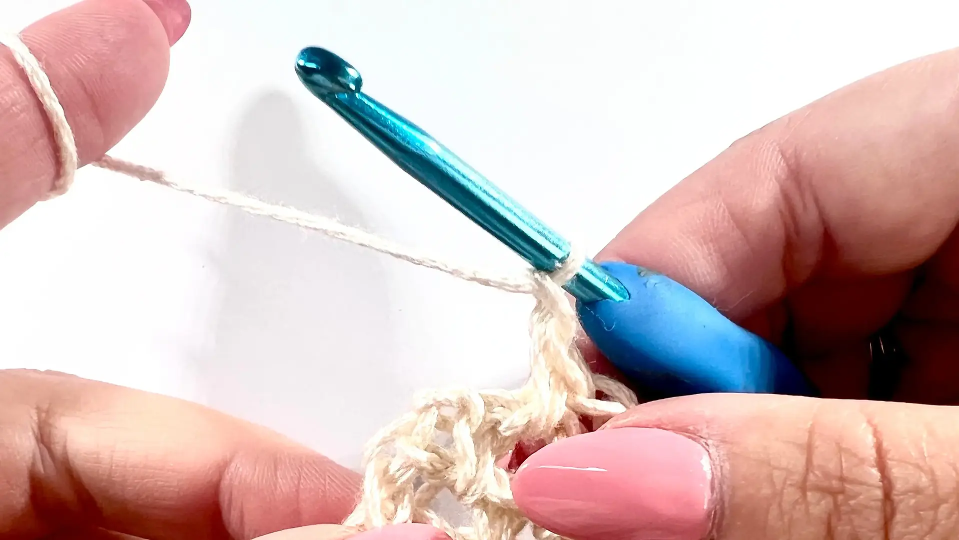  Close-up of a crochet hook holding two loops from the last single crochet stitch, ready to finish the stitch with a new yarn colour.