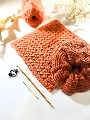 Beginner crochet dishcloth and scrunchie with yarn, hook, and tools on a white background