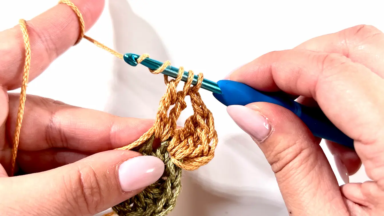 Close-up of crocheting the third petal for the Daisy Square, holding five loops on the hook.