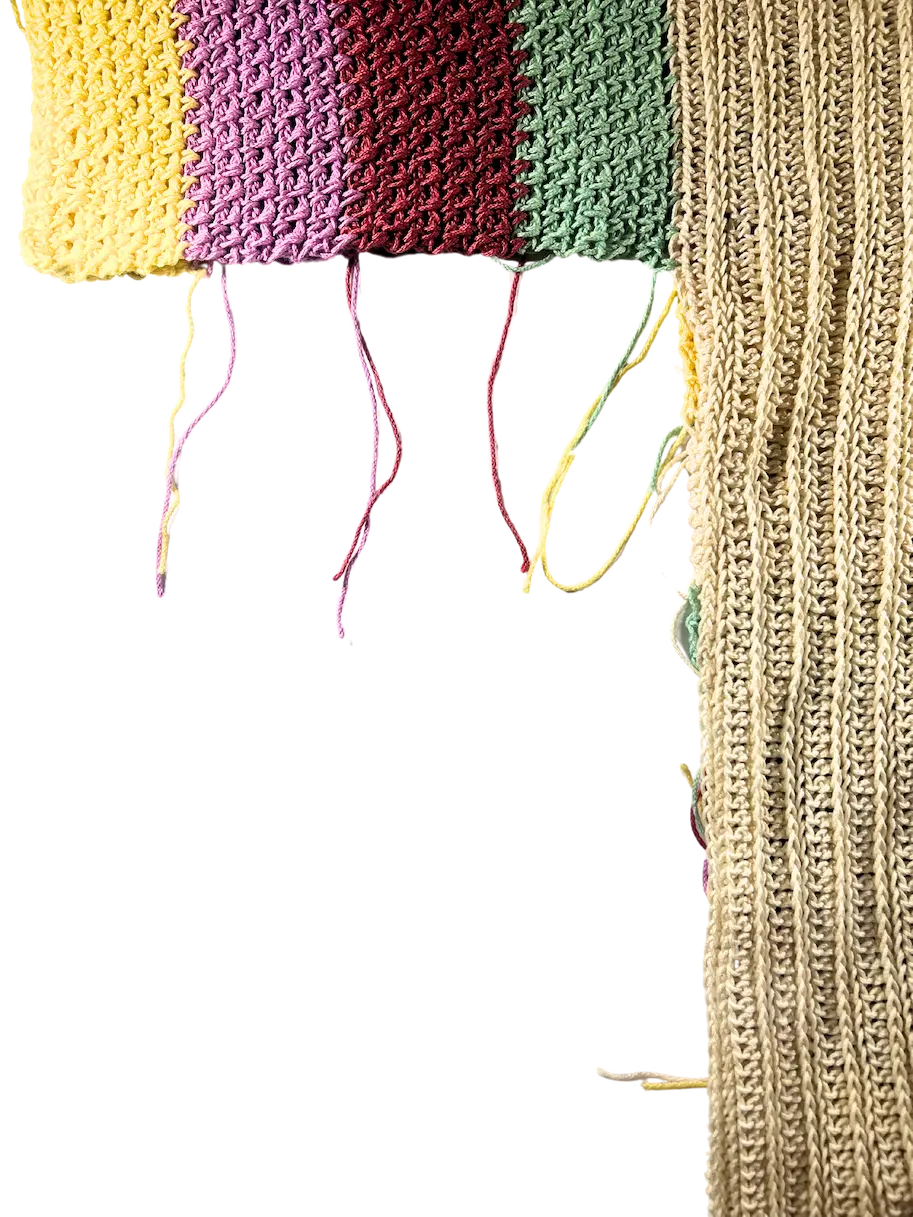 Close-up of the striped front panel and solid back panel aligned vertically, showing yarn tails positioned for seaming the side of the sweater from the hem upward.