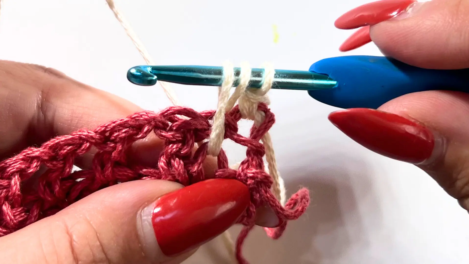 Close-up showing cream yarn loop pulled up to row height while making the first spike stitch.