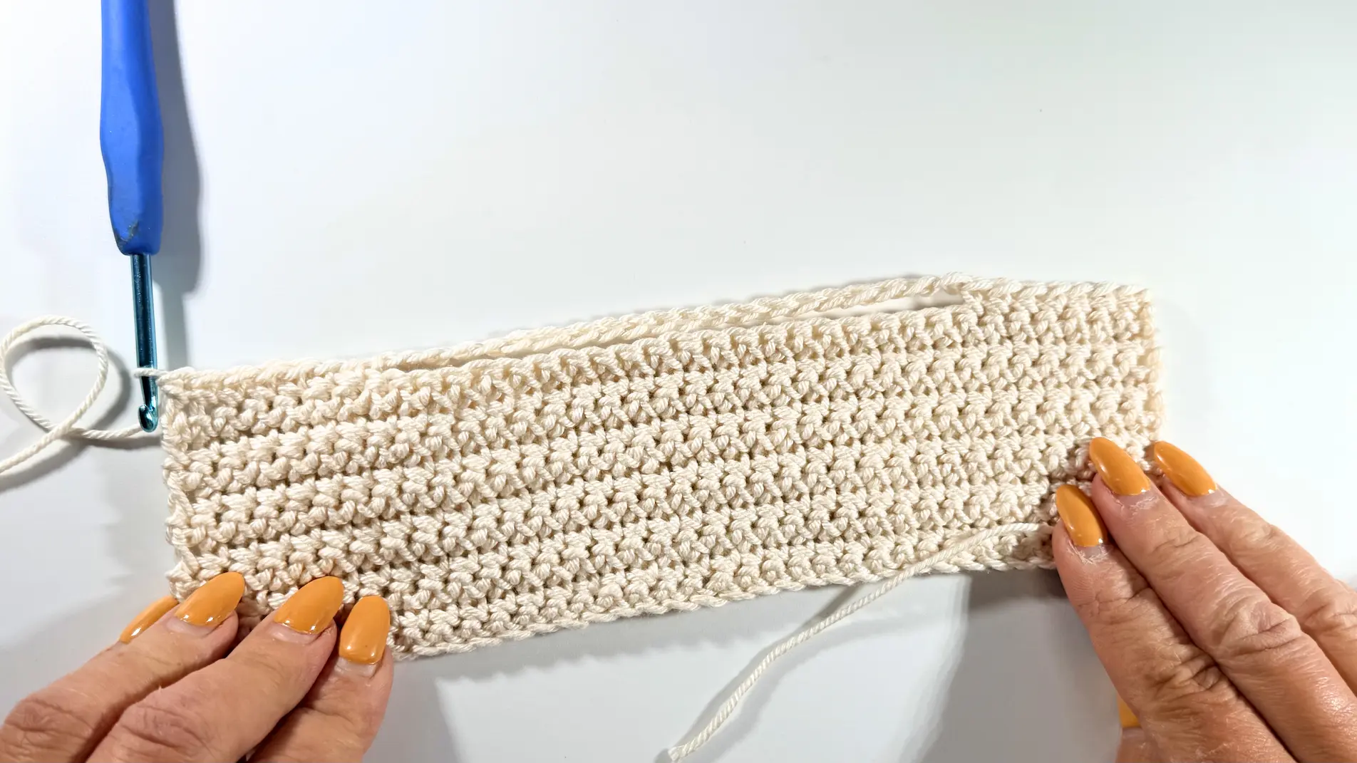 Close-up of a crochet rectangle showing the chain section stretched above the fabric to create an opening.