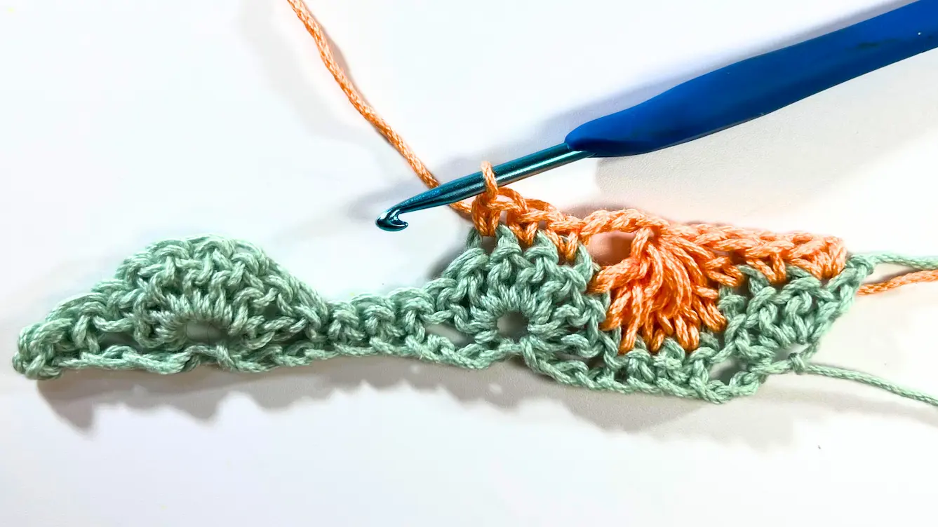 Catherine Wheel Stitch tutorial showing the work after completing 3 SC. The crochet hook with orange yarn is positioned above the stitches, ready for the next step.