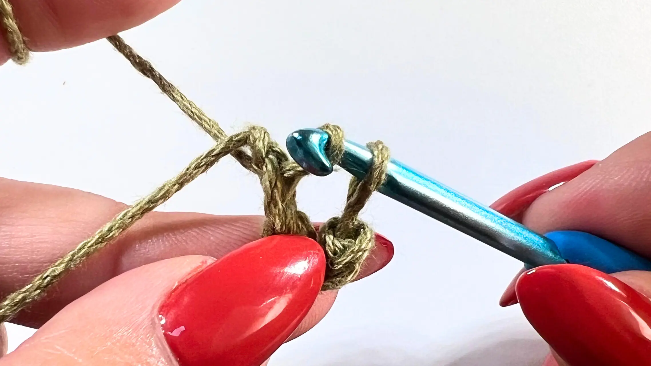 Crochet hook inserted into loop with yarn, starting the loop with slip stitch for granny square.