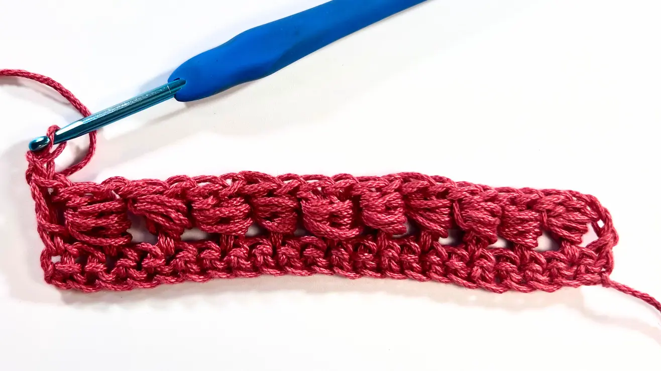 Completed first row of bead stitch crochet with alternating bead clusters and double crochets, ready to start the next row.