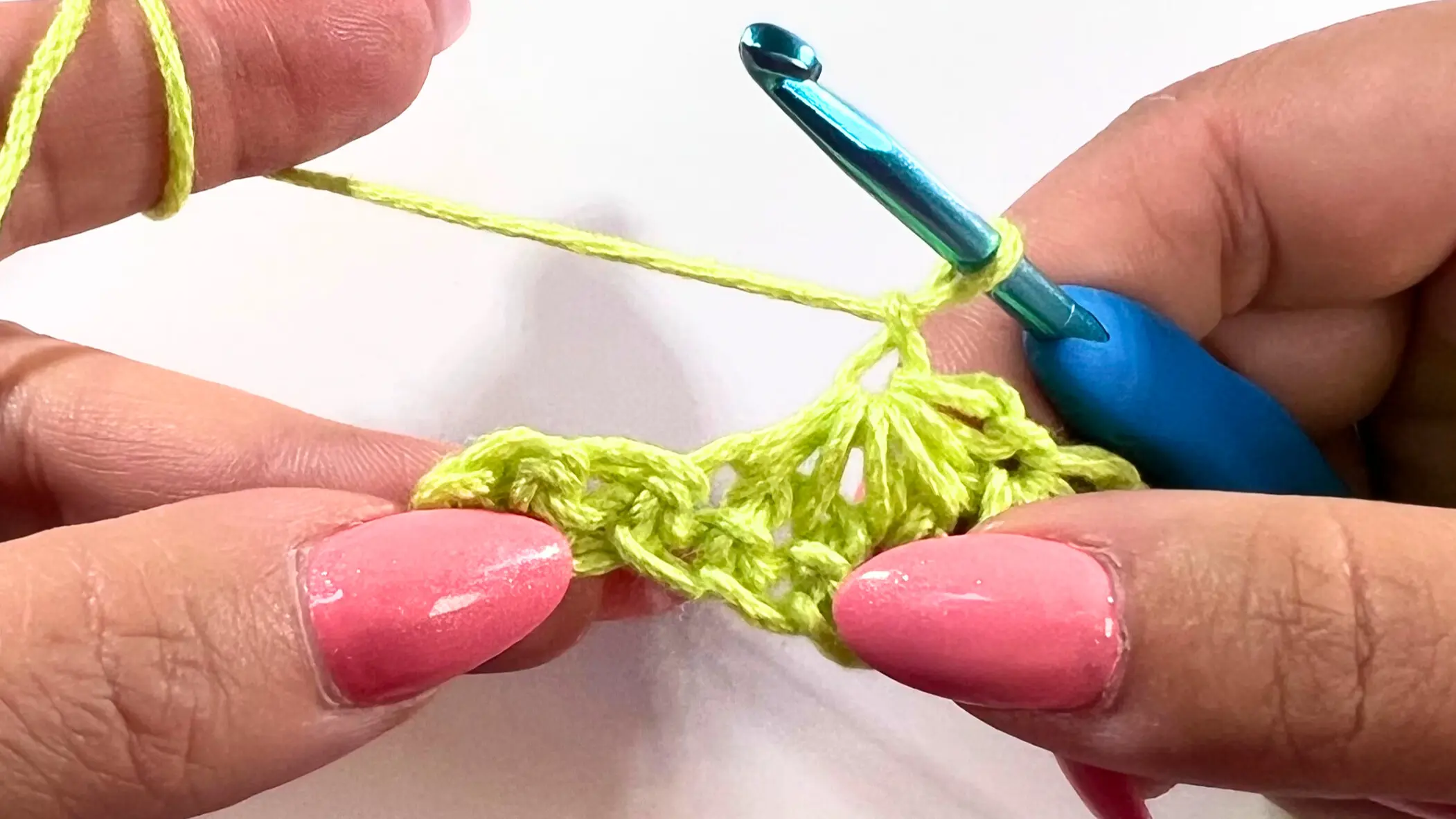 Crocheter preparing to work the last Star Stitch into the final stitches of the row, with hook in place above the previous cluster.
