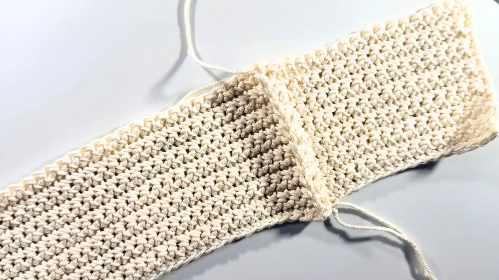 Long crochet panel and short crochet panel joined together to form a corner of the tissue box cover.