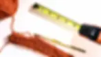 Crochet hook, yarn, and tape measure used for checking crochet gauge