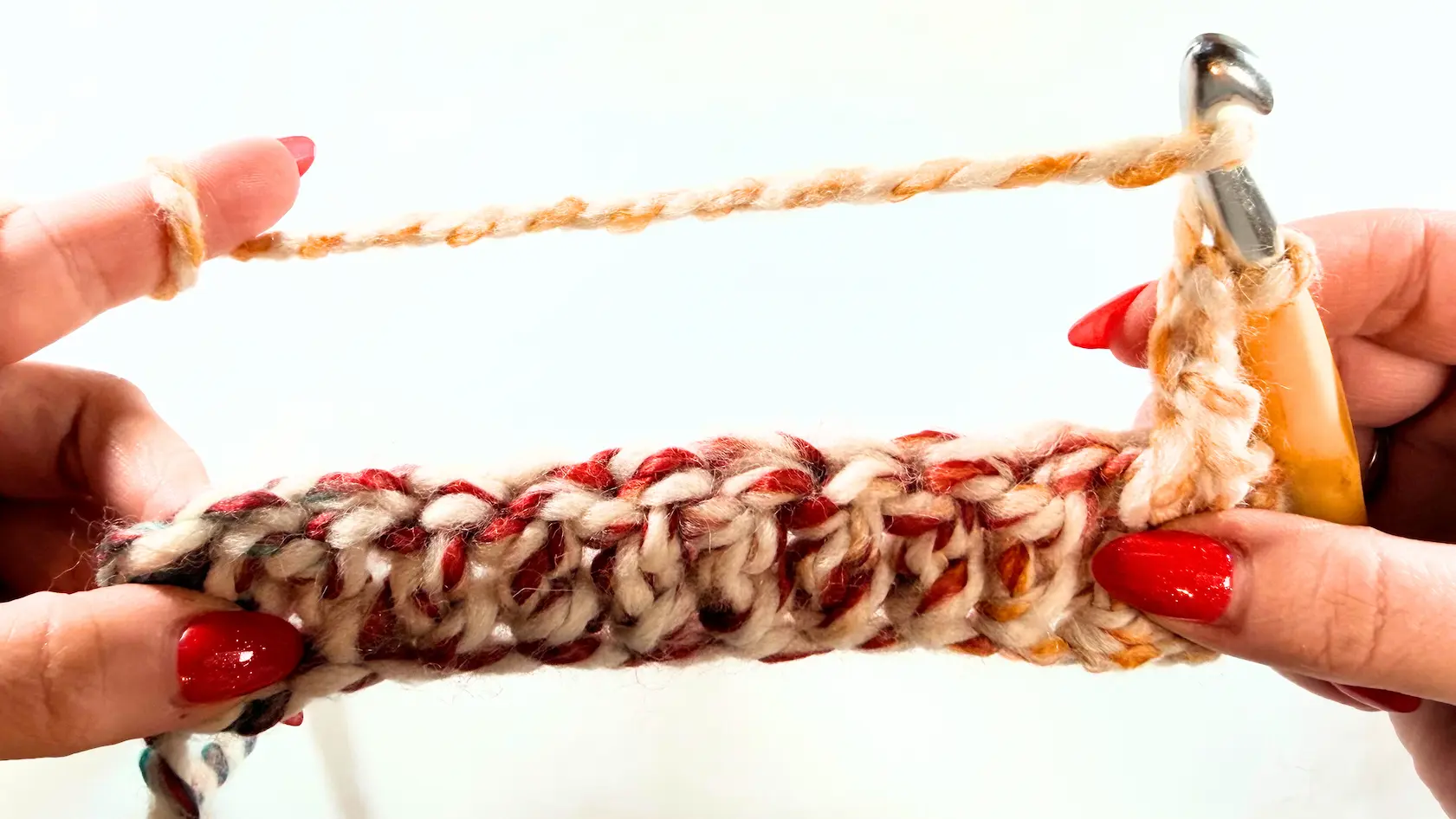 First row of chunky crochet hat completed in super bulky yarn, showing thick textured stitches worked flat and beginning of the second row.