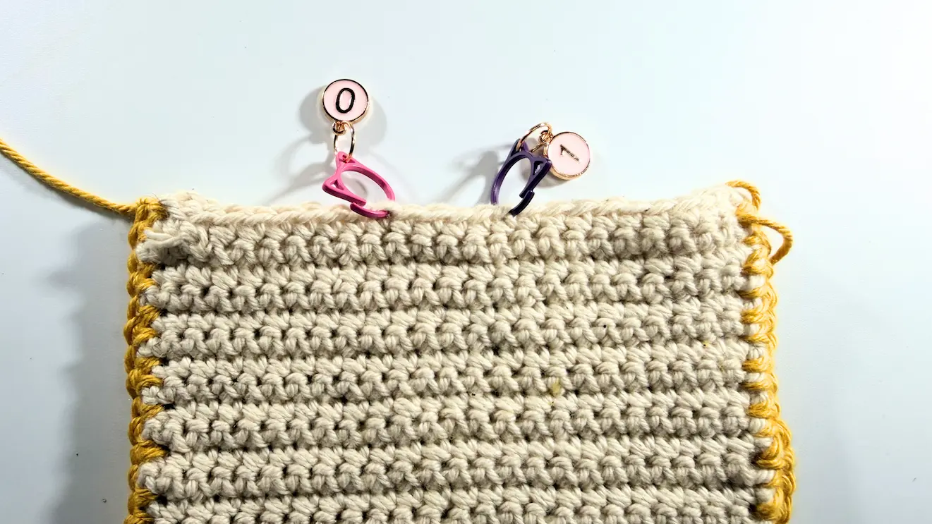 Using stitch markers to find and mark the center of the crochet Kindle sleeve for the closure placement.