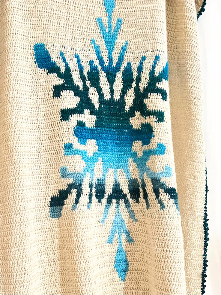 Crocheted blanket with gradient blue snowflake.