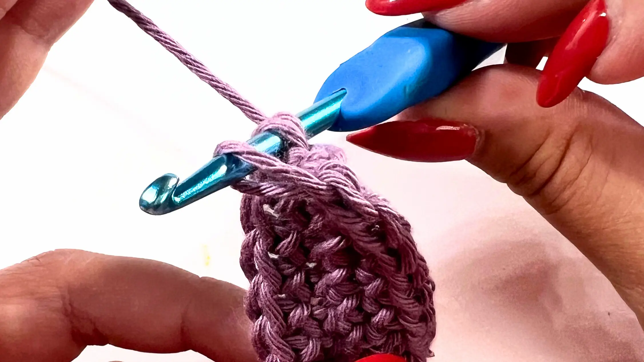 Close-up of crochet hook pulling loop through stitch for invisible join.