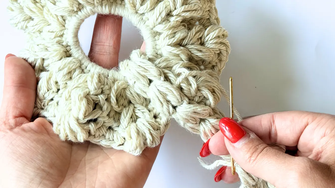 Use a yarn needle to sew the crochet heart tail securely onto the crochet heart scrunchie.