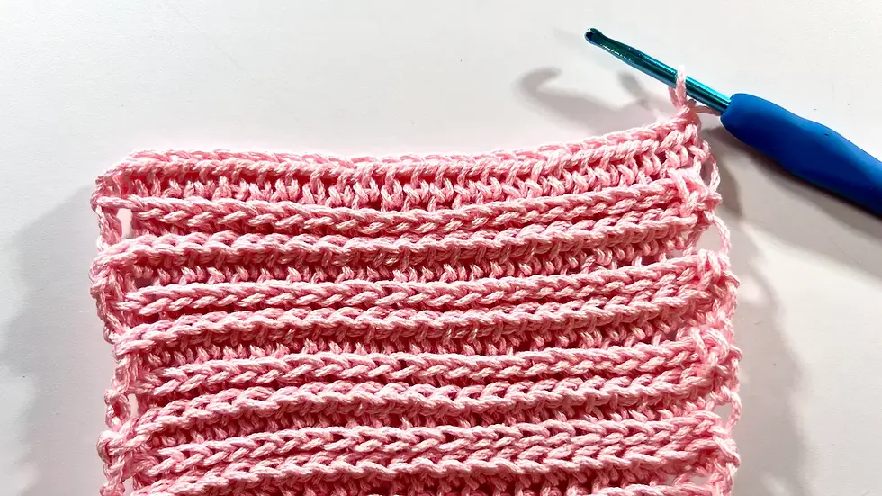 Close-up of a crochet swatch made with the camel stitch, showing horizontal ridges and textured rows in light yarn.