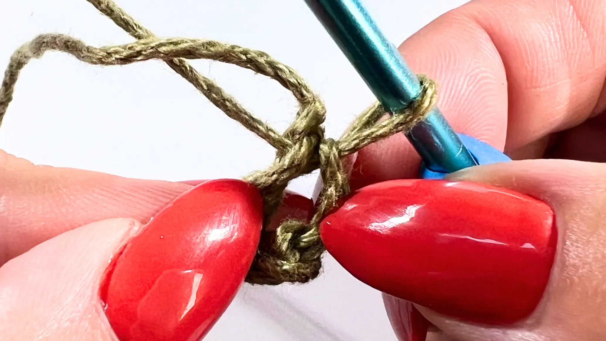 Crochet hook pulling yarn through the chain loop to create the ring for the granny square.