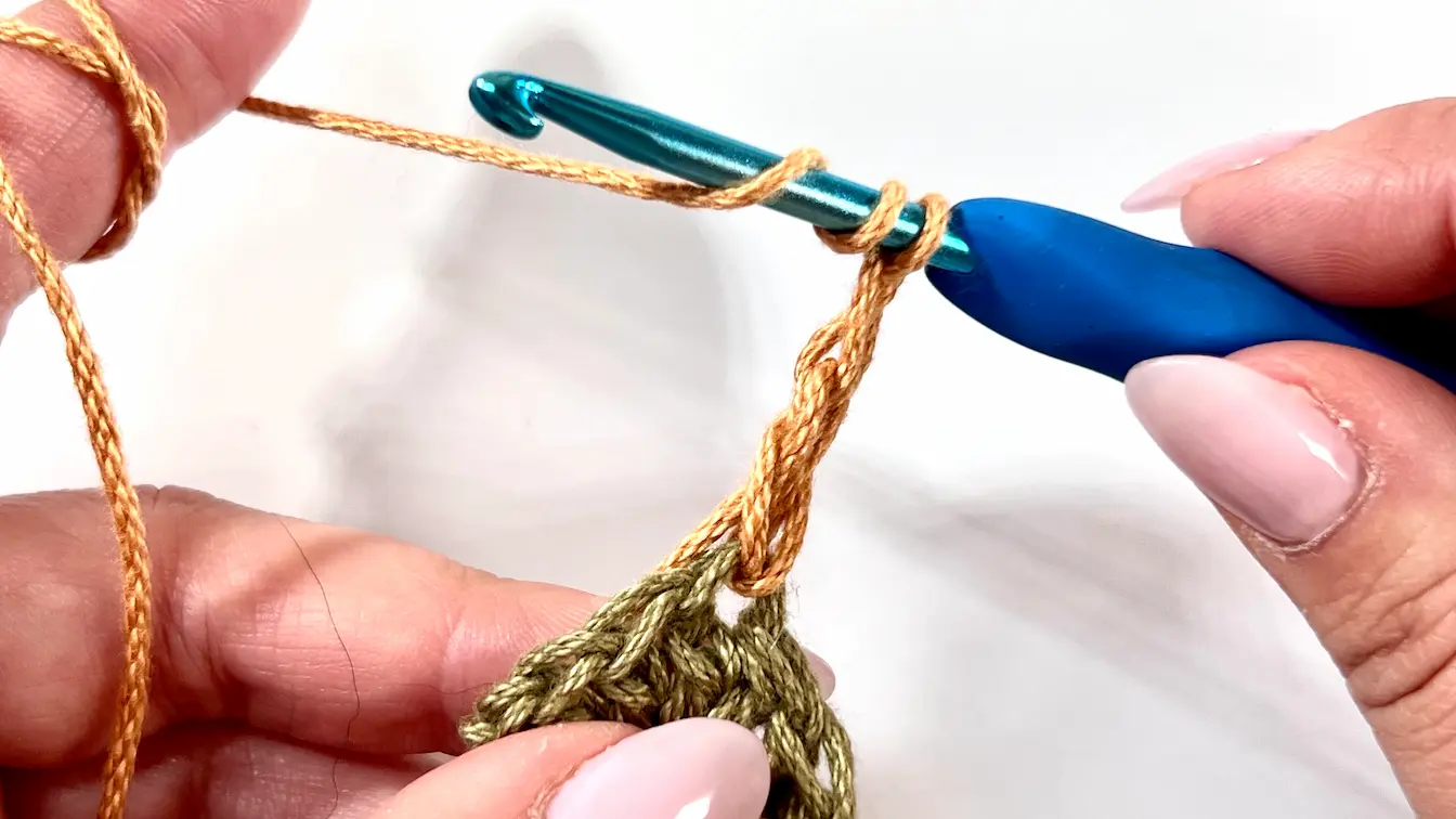 Crocheting petal stitches into the Daisy Granny Square using a golden yarn, shown in a step-by-step tutorial.