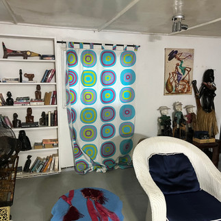inside lounge of White bench with zebra cushions and a backpack. Colorful abstract painting on the w