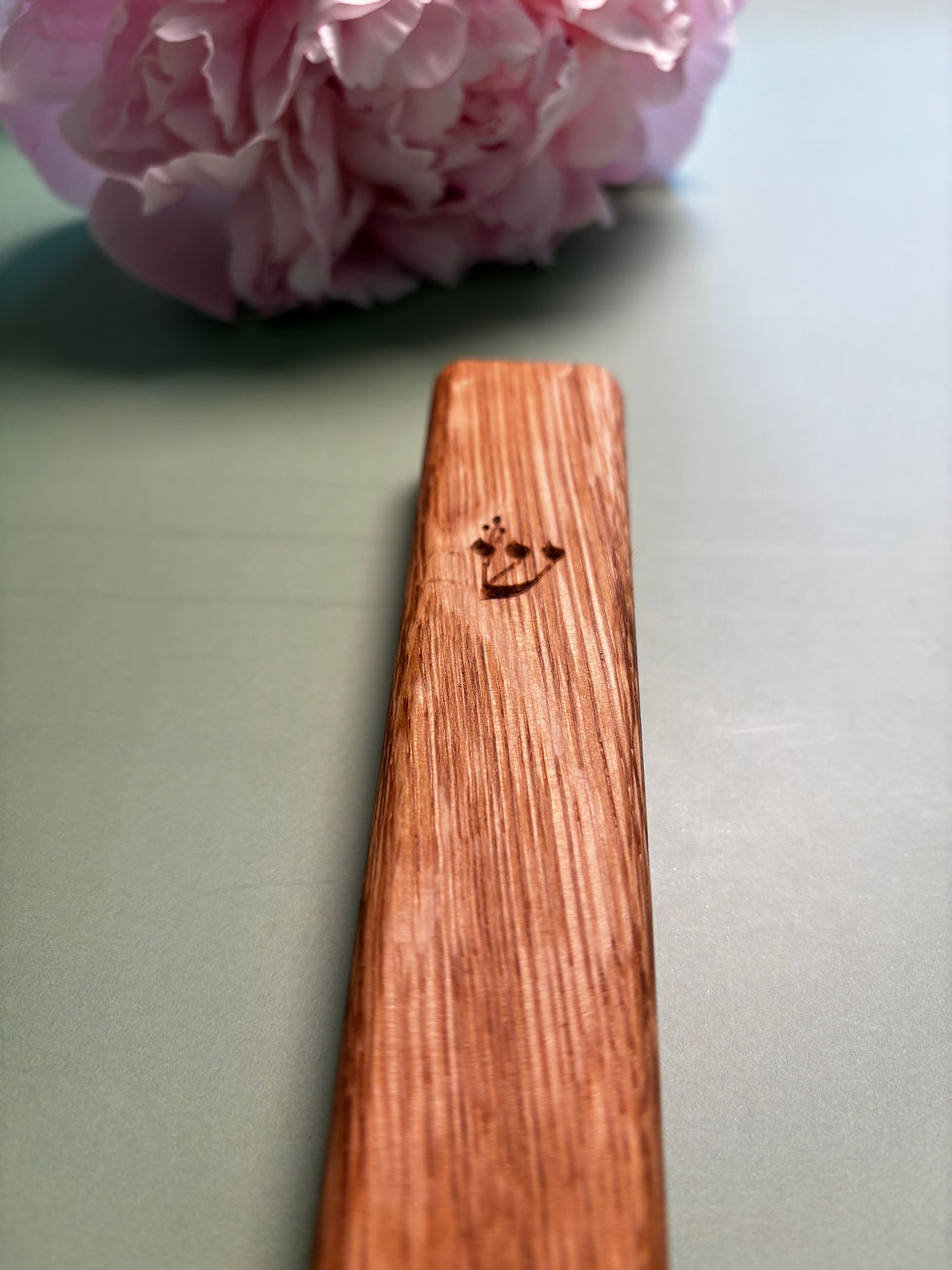 Thumbnail: Handmade wooden mezuzah on a light green background, with a pink flower accent, combining Jewish heritage with refined design