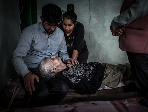 Eine alte Indische Frau auf dem Sterbebett, umgeben Ihrer Familie, die sterbende Frau hat den Kopf auf den Knien Ihres Enkels, der Sohn steht auf der rechten Site des Bildes mit verschränkten Händen. OBTAINING MOKSHA