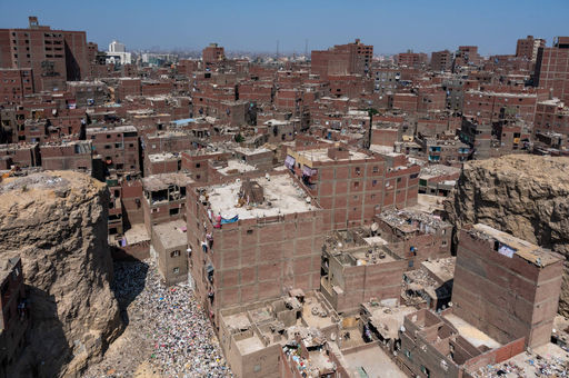 Luftaufnahme eines dicht bebauten Stadtviertels mit roten Backsteinbauten, dazwischen eine enge Müllschlucht
