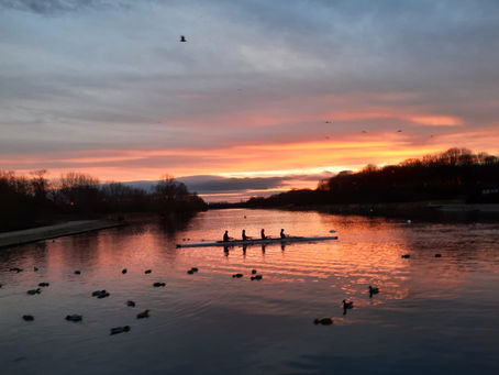 Rowers on a lake with the sun setting. The calm, peace and serenity that hypnotherapy can help with