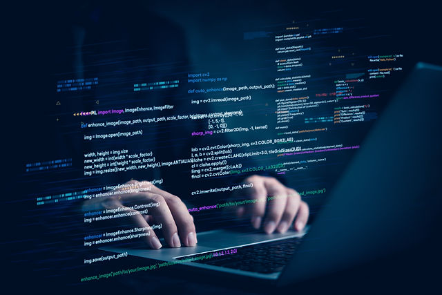 Hands typing on laptop with programming code on screen, representing software development.