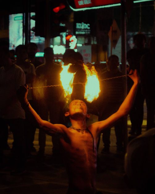 A street performer playing with fire surrounded by crowd at Bukit Bintang street