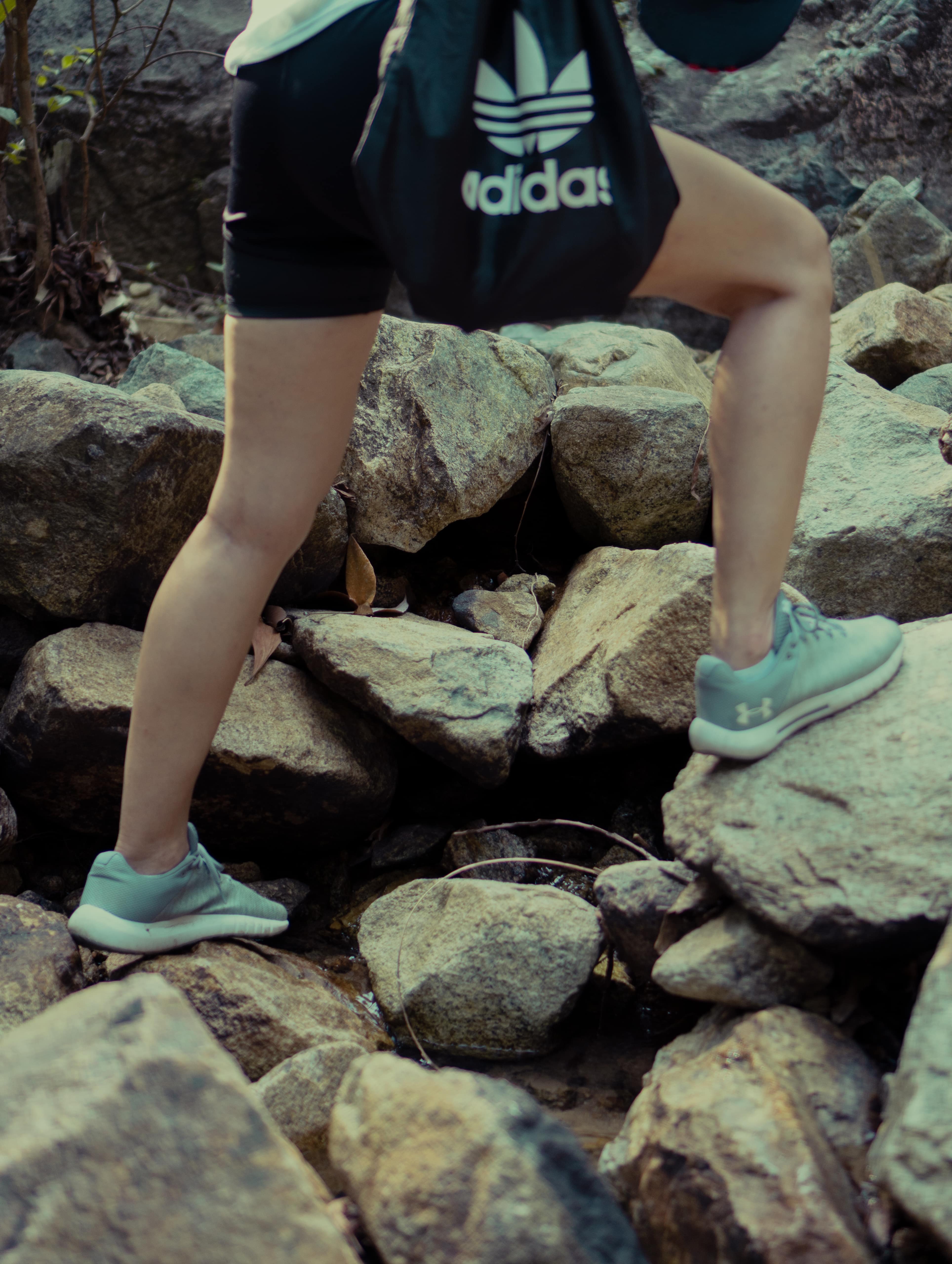 A hiker stepping on the stones with Under Armour shoes