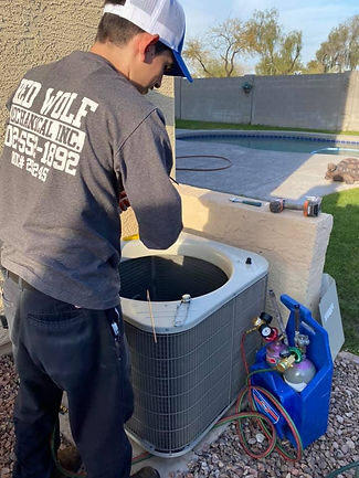 Red Wolf Mechanical technician preparing to recharge an A/C unit with refrigerant during a cooling system inspection in a Pho