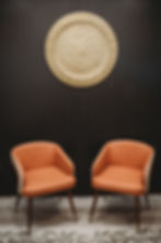 2 orange chairs in seating area with black wall