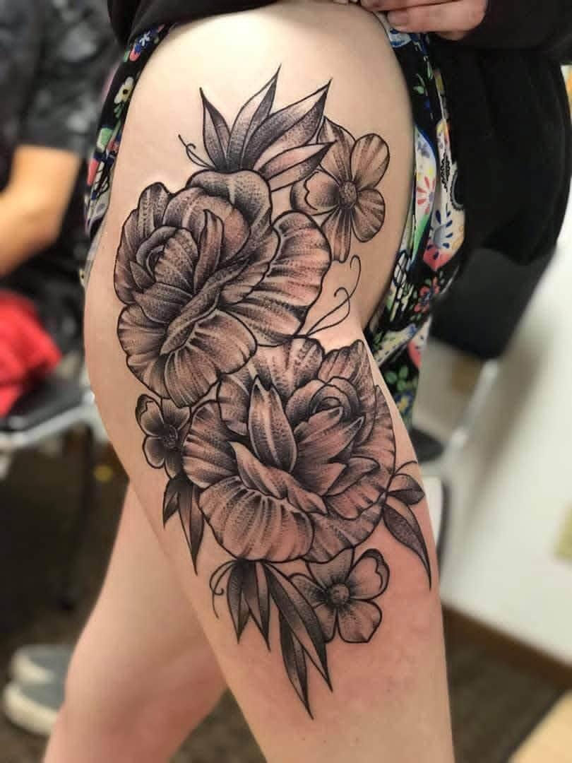 Floral tattoo displayed on a thigh, featuring intricate flowers, Lucky's tattoo work, detail.