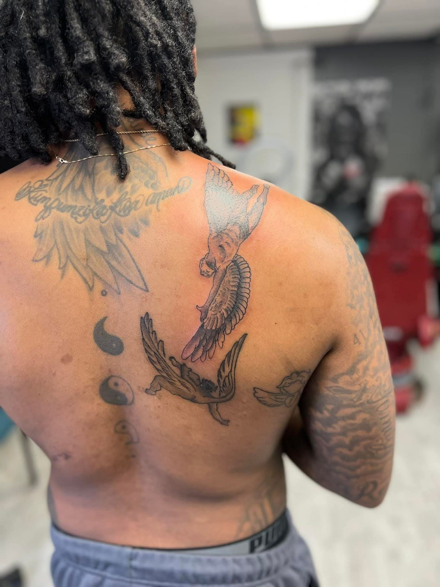 Man's back tattoos. Lucky's tattoo work is seen with detailed artistic designs.