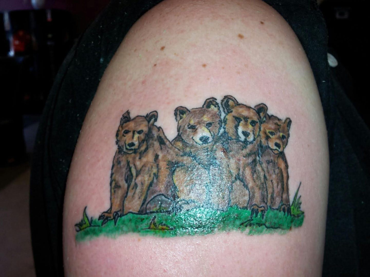 Four grizzly bears tattoo on shoulder in green grass, American Adrenaline.