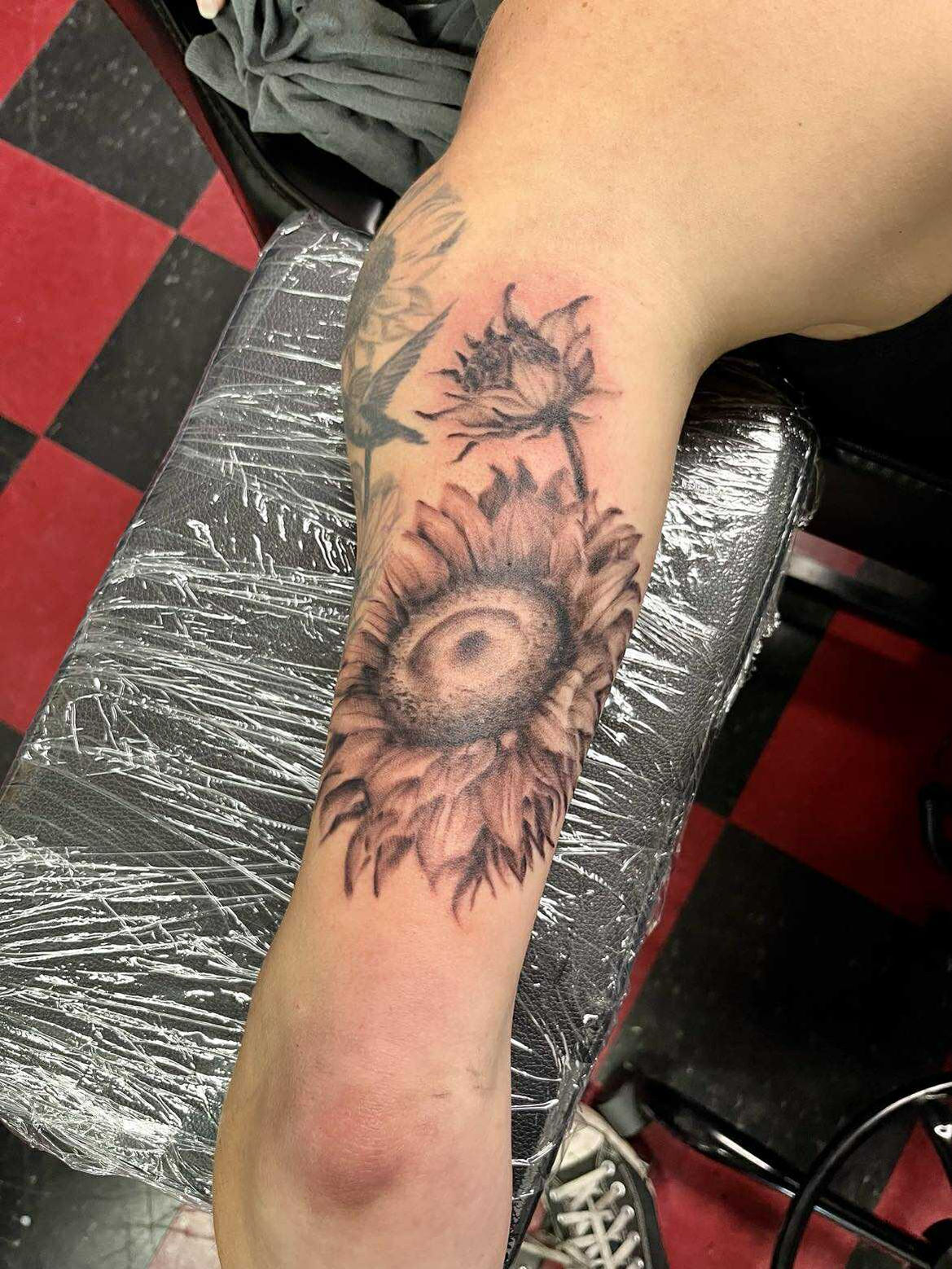 Close-up of a sunflower tattoo, detailed ink on arm, American Adrenaline.