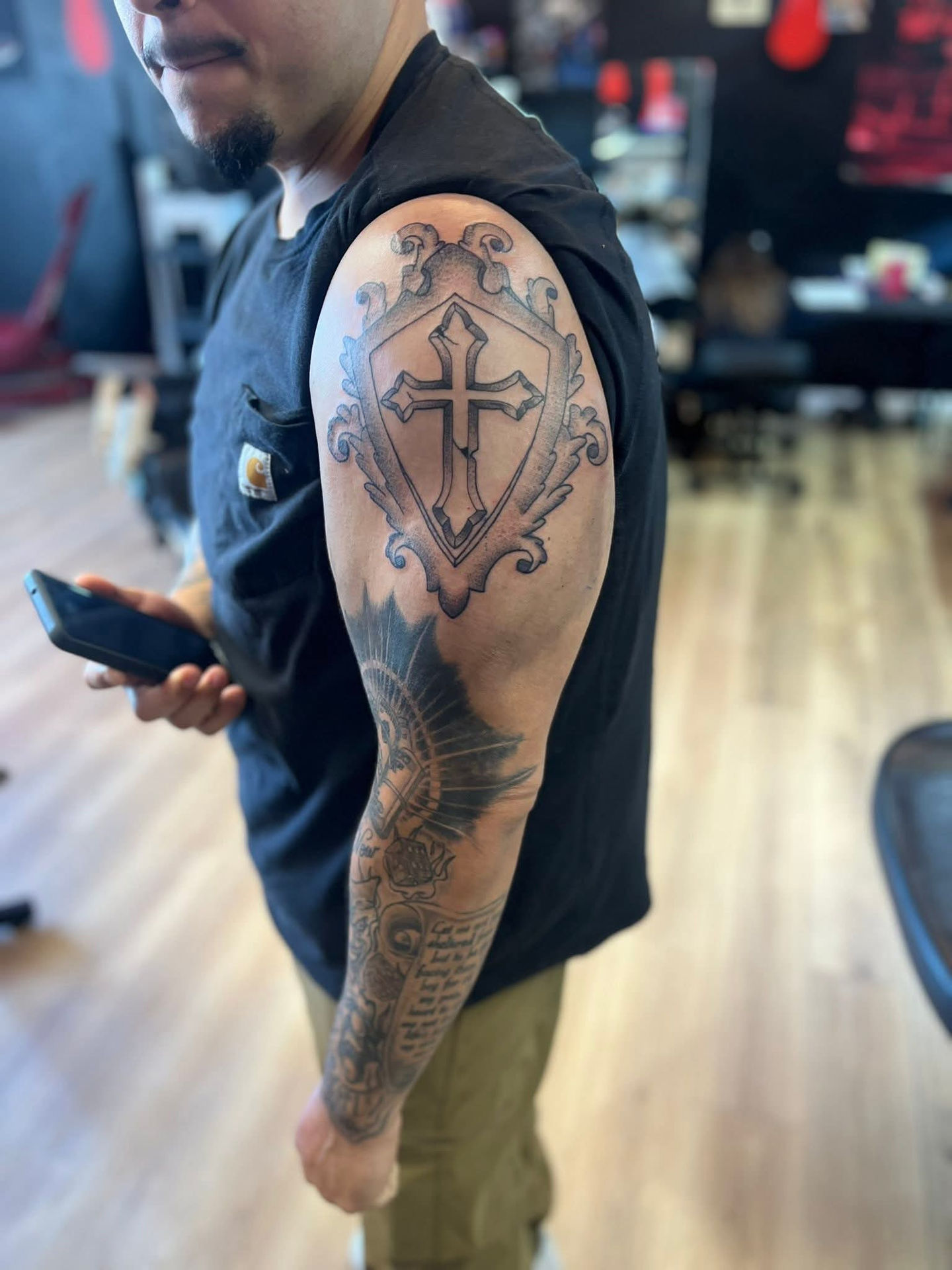 Man with large cross and anchor tattoo on his arm, Lucky's tattoo work.