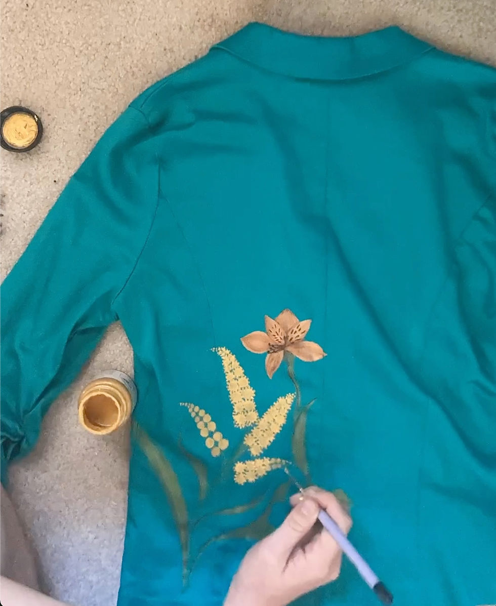 A hand painting a floral design on a jacket