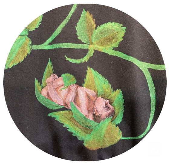 Close up detail of a hand-painted dress. A baby nestled in green leaves on a dark background, creating a serene, nature-inspired scene with vibrant greens and soft textures.