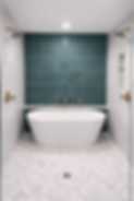 Modern bathroom with freestanding tub, teal tiled wall, brass fixtures, walk-in shower.