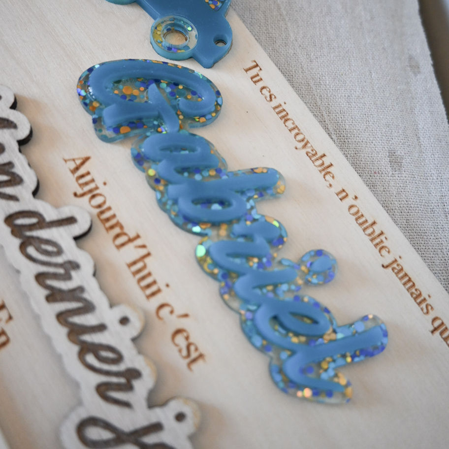 Zoom sur le prénom en plexiglass découpé, apportant une touche élégante et personnalisée à la pancarte de rentrée.