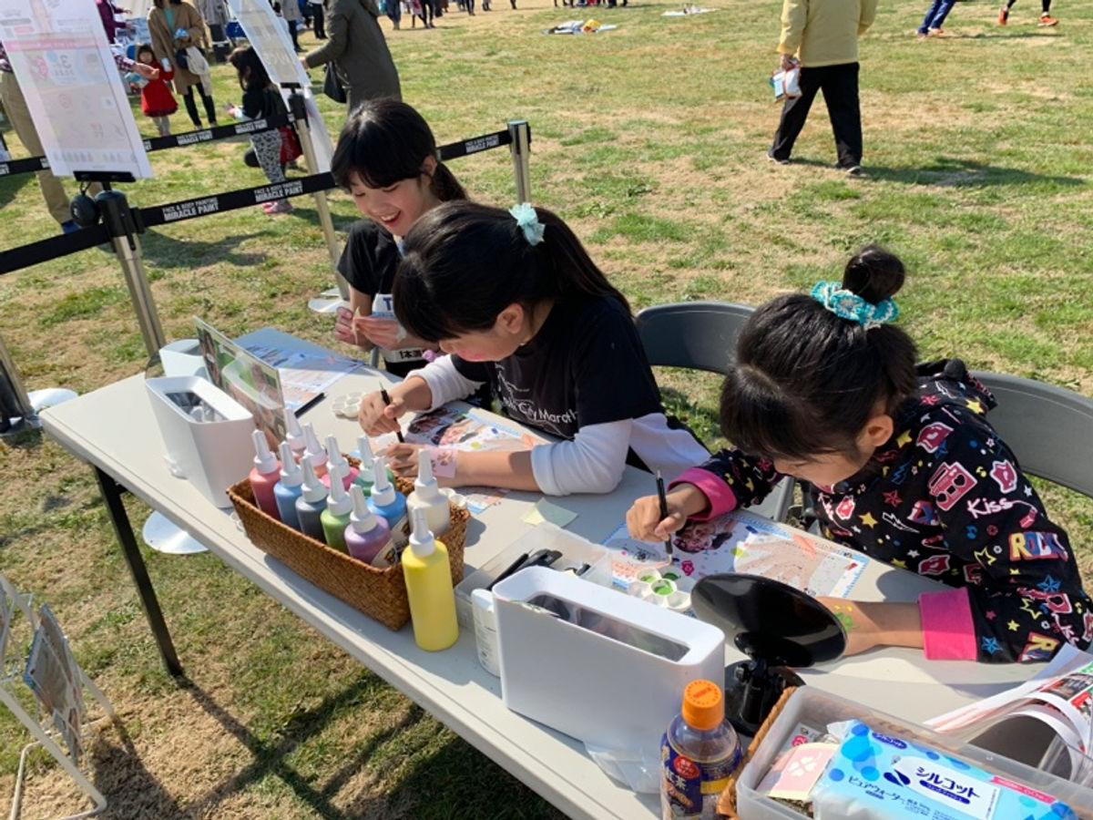 屋外のセルフペイントコーナーで子どもたちが自分で描いている
